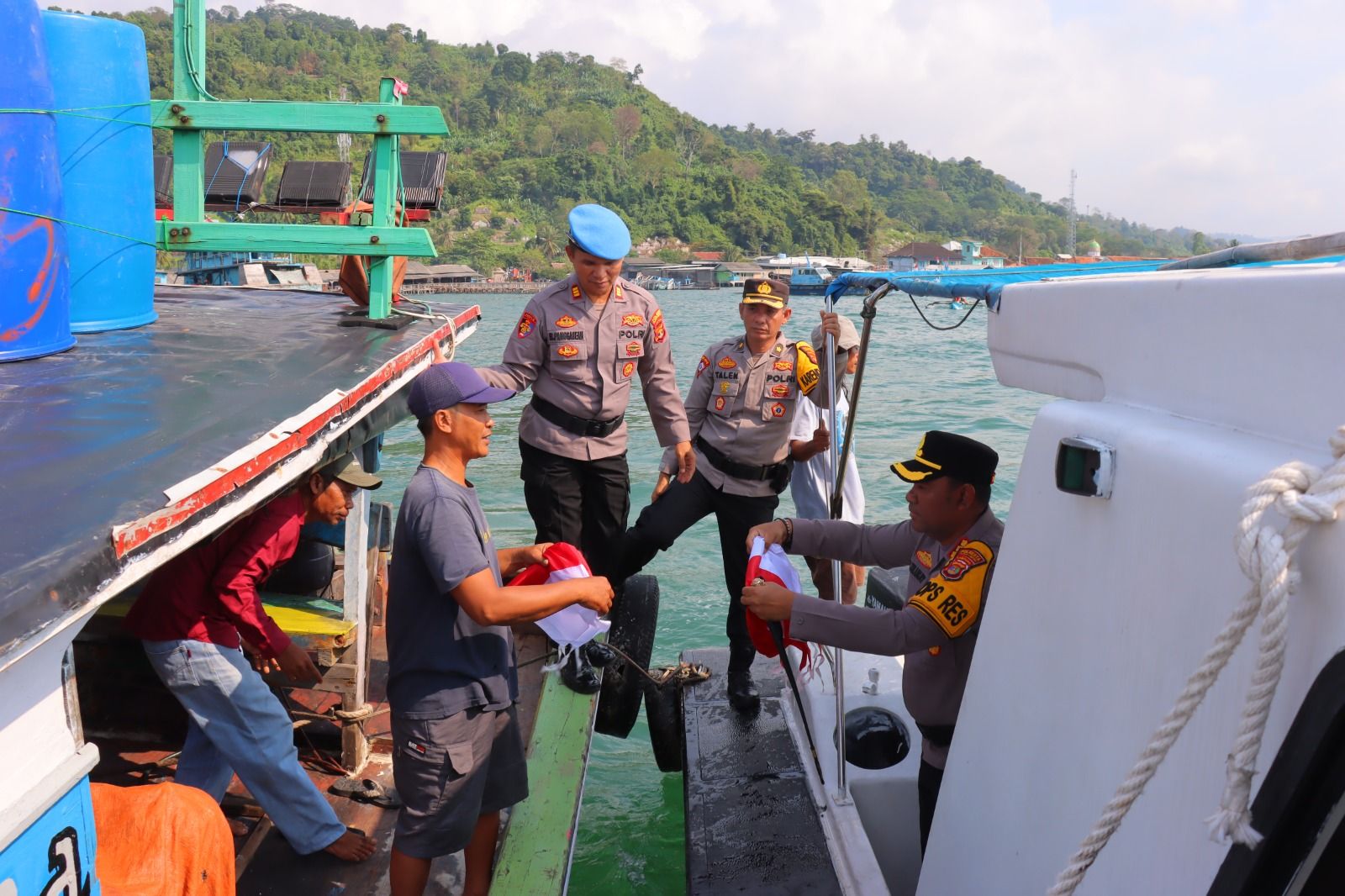 Kapolresta Bandar Lampung Kombes Pol Alfret Jaocb Tilukay membagikan bandera merah putih kepada nelayan di perairan Teluk Pesisir Lampung